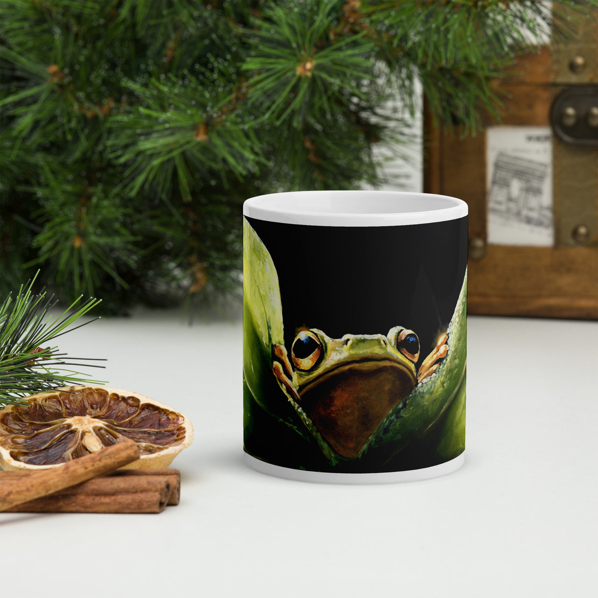 Leaf Me Sittin' - Mug by Aronja-Art black mug with cute frog artwork on a patio background