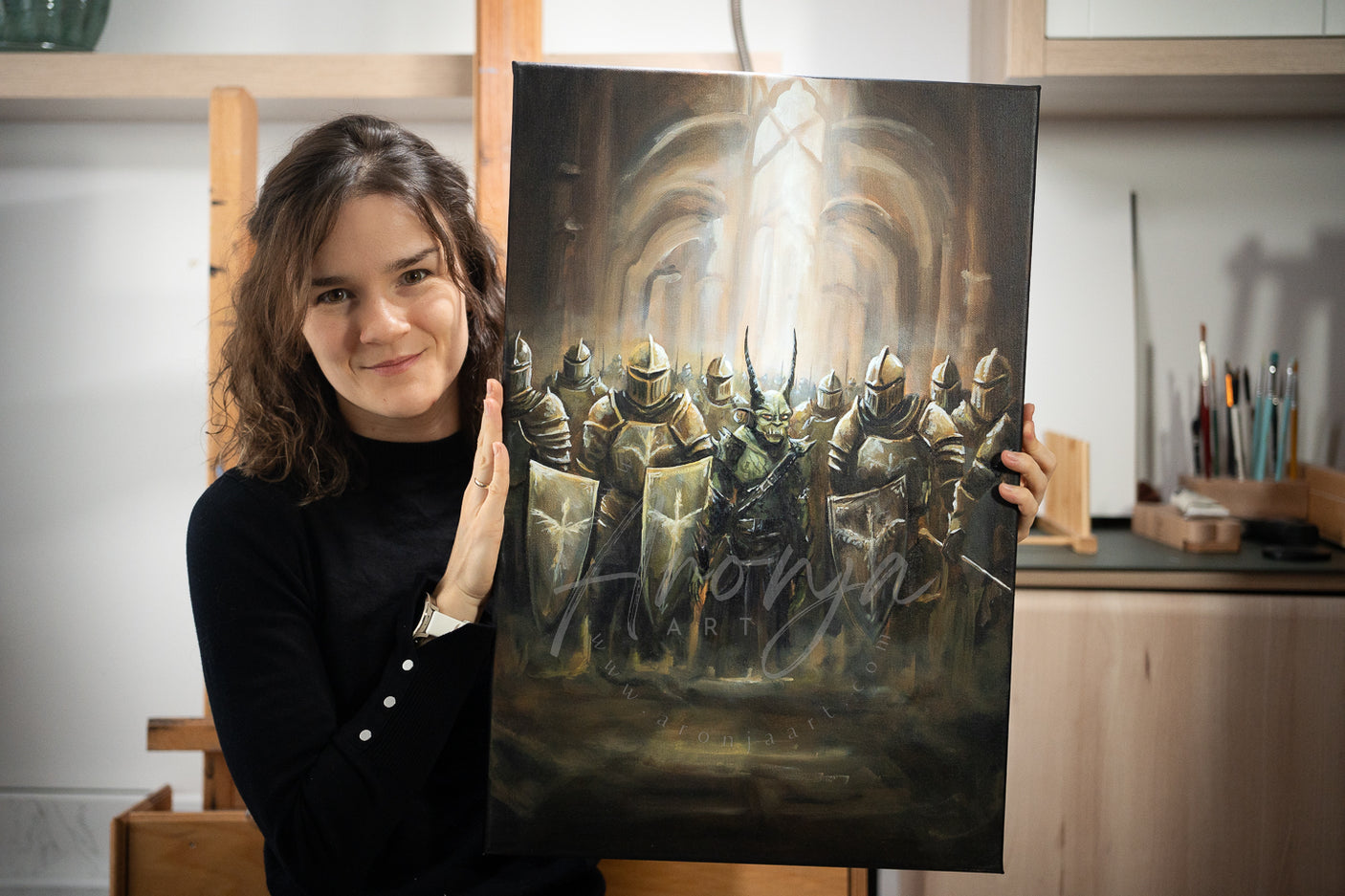 Woman holding SORCERY Gothic Original Painting "Swap" - 60x40cm / Acrylics depicting a group of armored knights in a dimly lit gothic setting, hand-painted fantasy art by a traditional artist inspired by gaming and mythical landscapes.