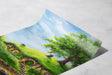 The Hole In The Ground - Print depicting a vibrant fantasy landscape with lush green hills, a large tree, and quaint hobbit-style round door homes under a bright blue sky.