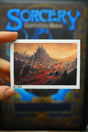 Hand-painted fantasy landscape featuring a dark, rocky terrain with a blood-red river under a glowing sunset sky, from Sorcery TCG Artist Proof "River Of Blood" #1/25. Fantasy and gaming art inspired by Lord of the Rings, Sorcery TCG, and nature.