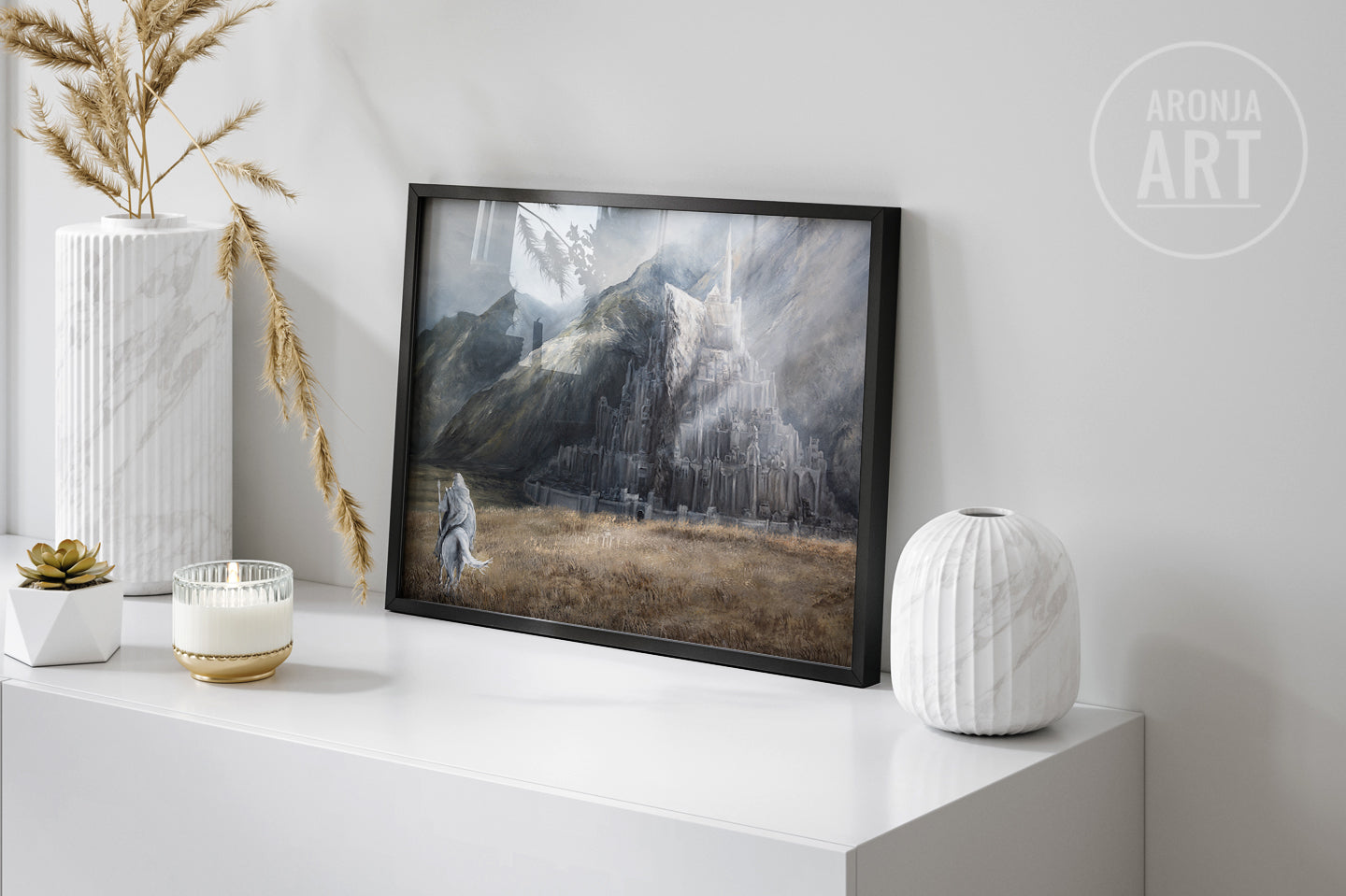 The City Of The Kings - (Print) features a fantasy landscape with a majestic mountain city under dramatic light, framed and displayed on a white modern surface beside decorative vases and dried grasses.