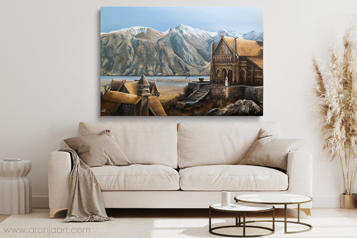 The Golden Hall - (Print) displayed above a beige sofa in a modern living room, featuring a detailed hand-painted fantasy landscape with medieval architecture and snow-capped mountains.