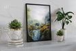 The Valley Of Imladris - Print showing a detailed fantasy landscape with waterfalls, lush greenery, and medieval-style buildings framed and displayed on a shelf with decorative plants.