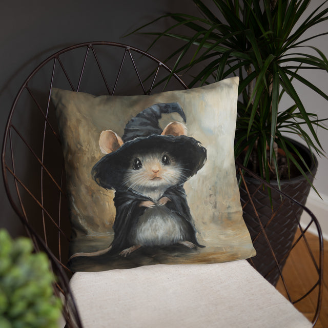 Mouse Wizard - Pillow featuring a detailed fantasy art illustration of a small mouse dressed as a wizard in a black cloak and hat, displayed on a chair with indoor plants in the background.